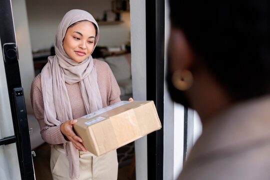 Woman wearing a hijab receiving a package at her front door