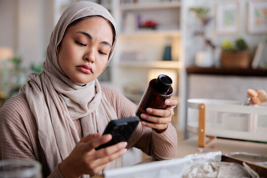 Woman in hijab checks product information on her phone.