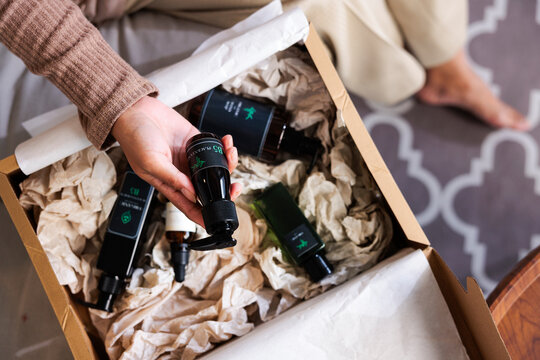Woman unpacking a box of organic skincare products.