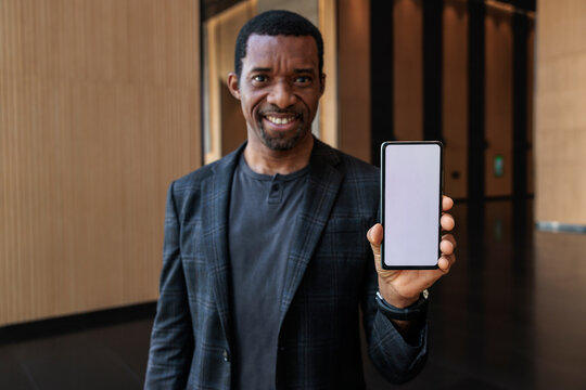 Smiling man presents a blank smartphone screen.