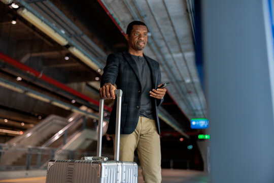 Man with suitcase and phone at train station.