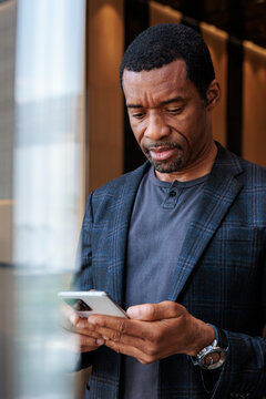 Man in blazer intently looking at his smartphone.