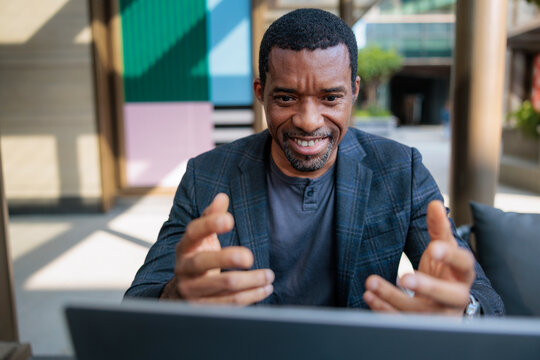 Man in blazer enthusiastically video conferencing on laptop.