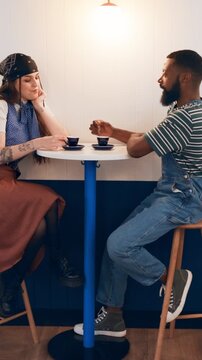 Happy couple, talk and date at coffee shop with drinks, bonding and relax with connection for love. Man, woman and interracial relationship with espresso, conversation and smile with chat at cafe