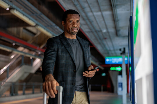 Man with luggage and phone at airport or train station.