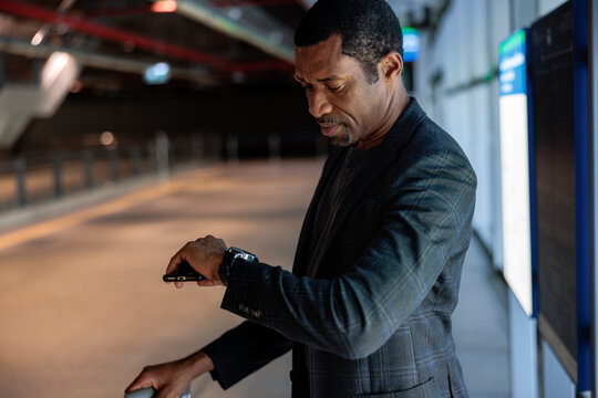 Man checks time while holding phone at transit station.