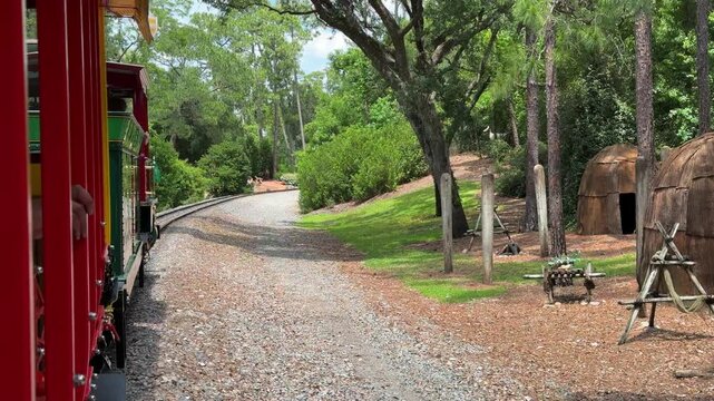 A railway track curves gently through lush greenery and trees. The peaceful scene highlights nature surrounding a historic train route.