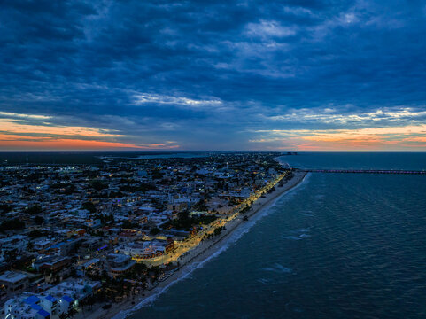 Aerial view of the illuminated coastal city of Progreso on the Peninsula de Yucatan at dusk with the long pier extending into the sea in Yucatan, Mexico.