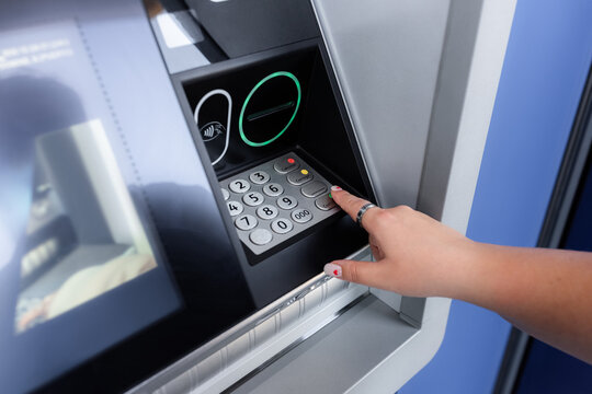 Woman entering pin code on ATM 