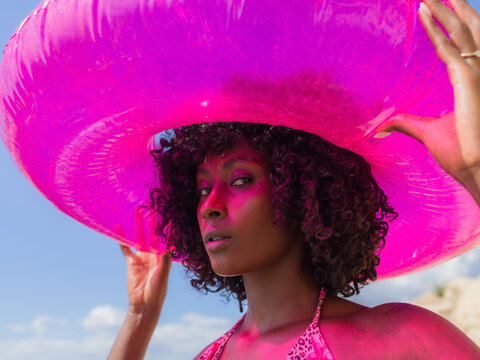 Woman posing with pink float at beach 