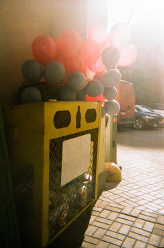 Red and Blue Balloons on Yellow Recycling Bin
