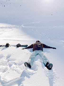 Man lying in snow beside snowboard