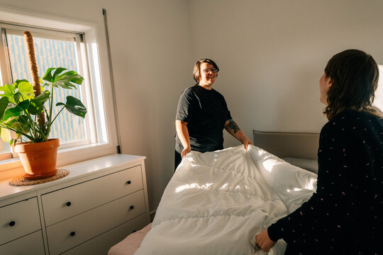Two People Making a Bed in a Bright Room
