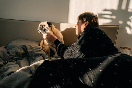 Woman Spending Time With Her Dog on a Bed in Morning Light
