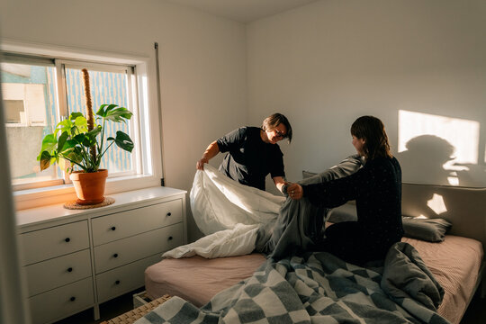 Light Fills a Room as Two People Make the Bed in a Home