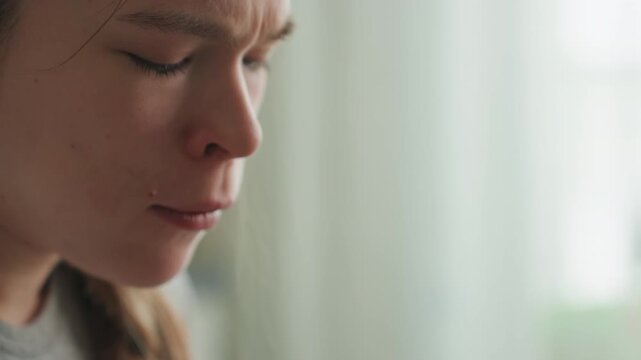 Pregnant woman tasting food with fork. Closeup study of flavor and texture evaluation, gentle grimace and small swallow, pale natural light in kitchen, expectant mother balancing cravings