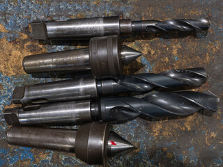 Assorted metal drill bits and live centers on industrial workbench © lucag_g