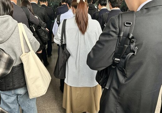 通勤ラッシュ時の駅のホーム、列に並んでいる通勤客