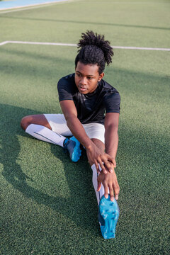 Young rugby player stretches on field before practice