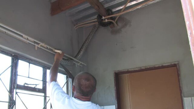 men carefully handle a massive African rock python From house Indoor Ceiling in a rural Botswana setting
