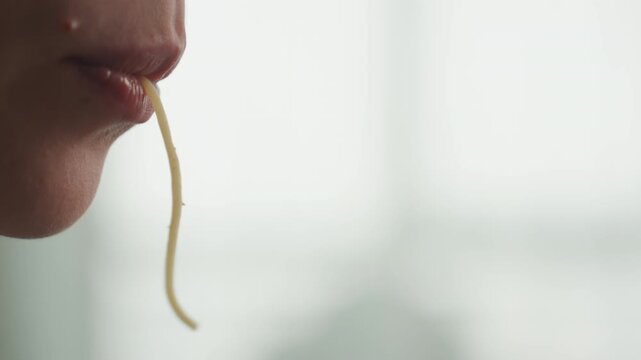 Closeup mouth noodle, caucasian pregnant woman, intimate profile shot with lips and noodle strand, subtle droplet and saliva glint, focused slow chew, sensory craving study, soft backlight, cinematic
