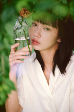 Chinese girl holding dried rose under a tree in garden,closeup