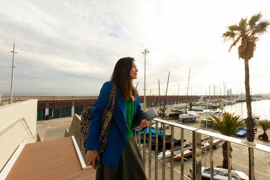 Woman Stands by Railing at Marina During Cloudy Day