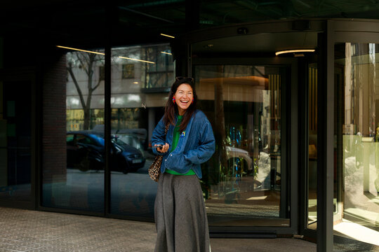 Woman Smiling Outside a Building in a City Park Area During Daylight