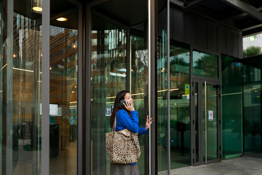 Woman Talking on Phone Near Building Entrance in Urban Area