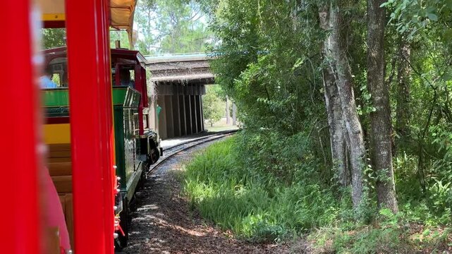 A vintage train travels along railway tracks toward a tunnel surrounded by forest. The scene captures adventure, transportation, and nature travel.