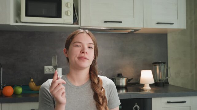 Female savors flavorful meal happily. Woman enjoys her delicious dinner pleasantly in warm kitchen. An individual female delights in tasting her meal within comfortable kitchen setting