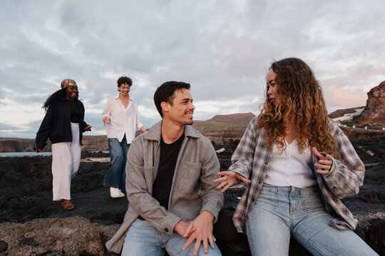 Group of friends talking on volcanic rock coast