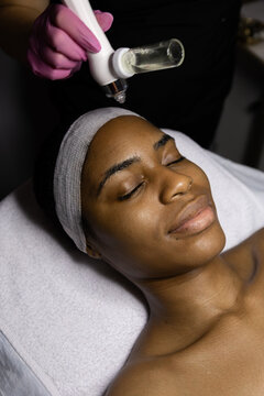 African woman in beauty clinic doing a facial evaluation and a cosmetology treatment. Woman on an esthetician appointment of facial. use mask do skincare routine