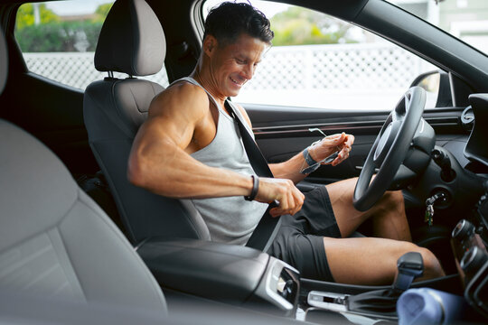 Man fastens seatbelt inside car
