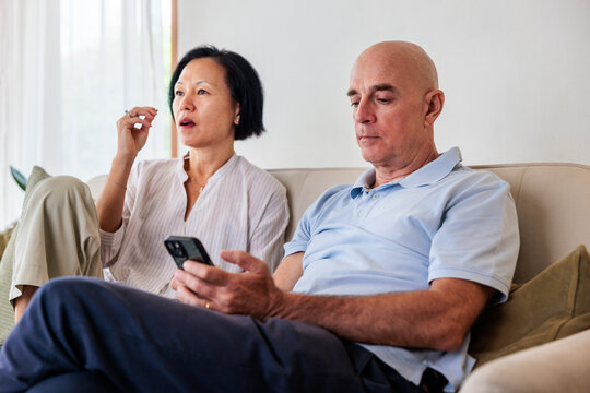 Couple relaxing on couch, man using phone.