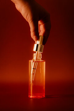 Hand holding a dropper in cosmetic bottle