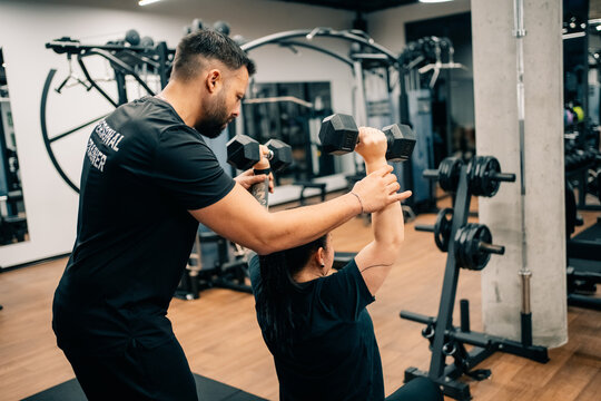 Personal Trainer Helps Client With Weight Lifting Session in Gym