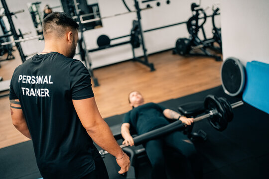 Personal Trainer Instructs Client During Weight Lifting Session in Gym