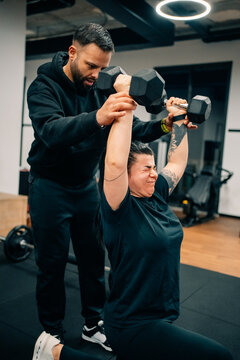 Personal Trainer Helps Client With Weightlifting in Gym Setting