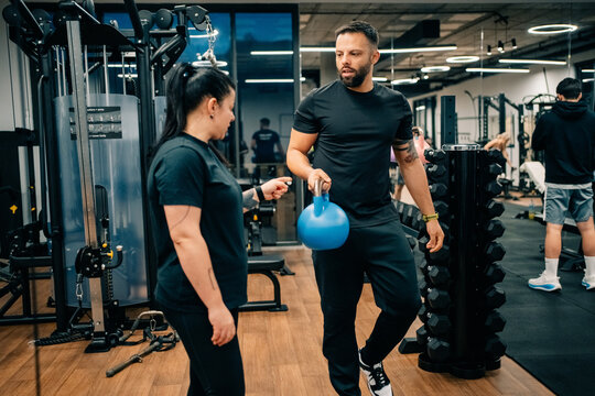 Man Brings Weight During Training Session in Gym With Student