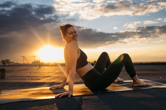 Woman Doing Sunset Yoga On Rooftop Mat