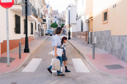 Woman and Girl Walking on a Crosswalk in a Quiet Street