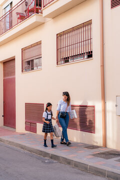 Mother Walks With Daughter to School in City Street