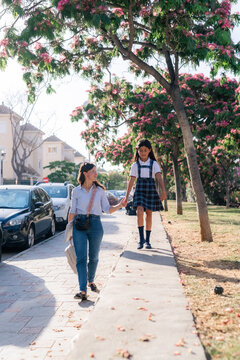 Child Walks Home From School With Mother Near Blooming Trees