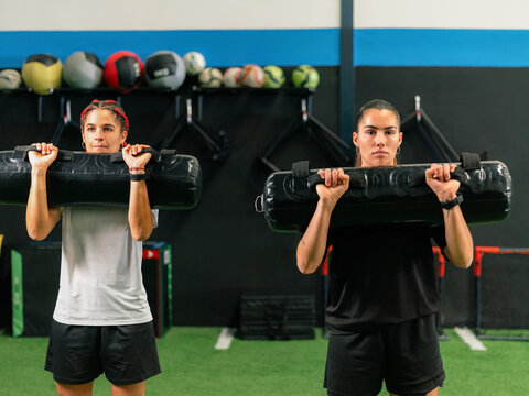 Women Exercise With Weights in Gym During Training Session