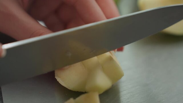 Hands dice pear. Carefully chopping pear on stainless surface. Dicing pear precisely on clean cutting board in kitchen. Tranquil kitchen setting with hands skillfully preparing fruit for salad