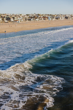 Rolling ocean wave along sandy beach with coastal homes
