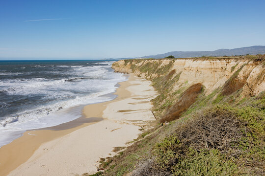 Expansive Coastal Cliffs and Sandy Beach Under Blue Sky