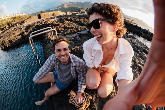 Travelers taking selfie laughing at natural rock pools