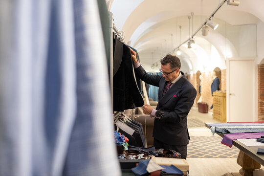 Senior man measuring jacket with tape in studio